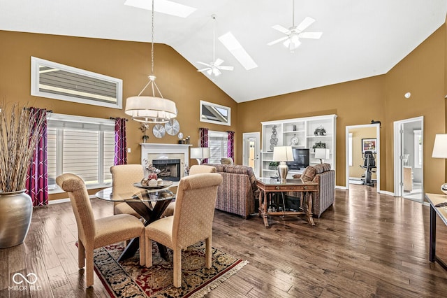 dining room featuring dark hardwood / wood-style flooring, a skylight, high vaulted ceiling, and ceiling fan