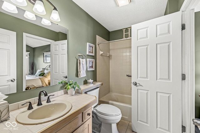 full bathroom with toilet, tiled shower / bath, a textured ceiling, vanity, and tile patterned flooring