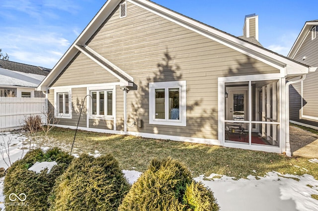 snow covered house featuring a sunroom and a yard