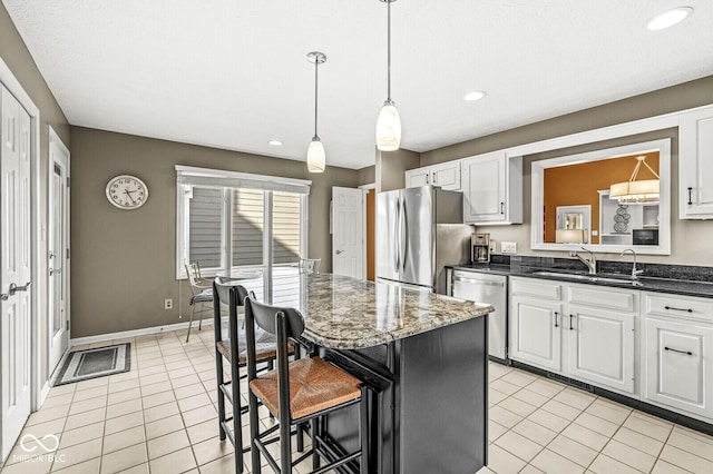 kitchen featuring sink, a breakfast bar, appliances with stainless steel finishes, white cabinetry, and light tile patterned flooring