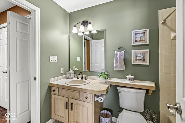 bathroom with vanity, toilet, and a tile shower