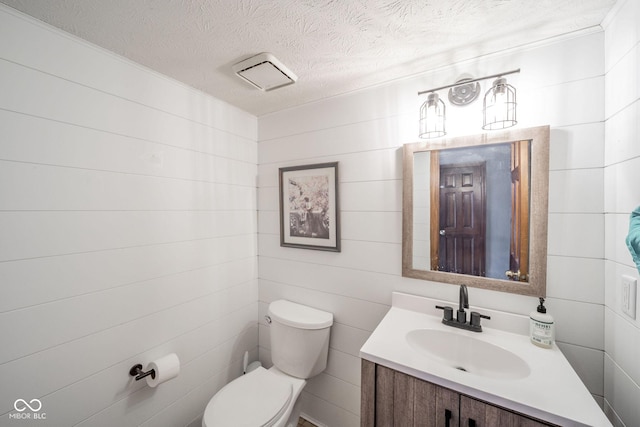 bathroom with toilet, vanity, and a textured ceiling