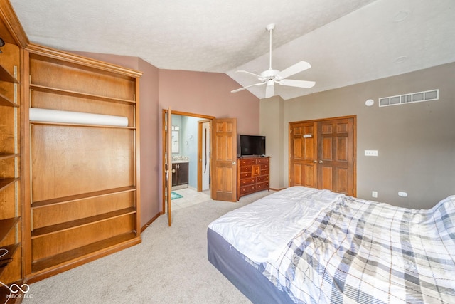 bedroom featuring ceiling fan, ensuite bathroom, light carpet, and lofted ceiling