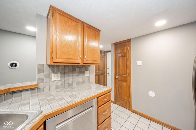 kitchen featuring decorative backsplash, dishwasher, tile counters, and light tile patterned flooring