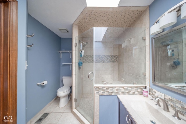 bathroom with toilet, tile patterned flooring, a shower with shower door, and vanity