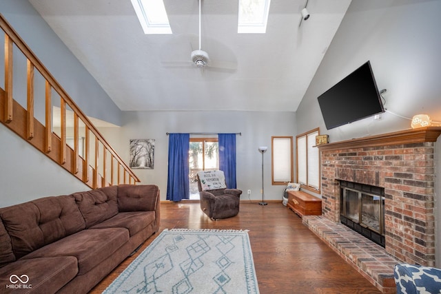 living room featuring ceiling fan, dark wood-type flooring, lofted ceiling with skylight, and a fireplace