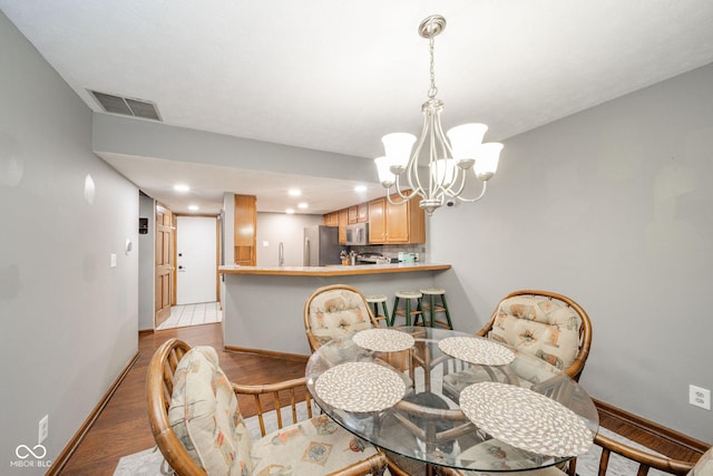 dining room with light wood-type flooring and a notable chandelier