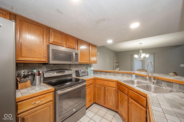 kitchen with a notable chandelier, tile countertops, sink, appliances with stainless steel finishes, and light tile patterned floors