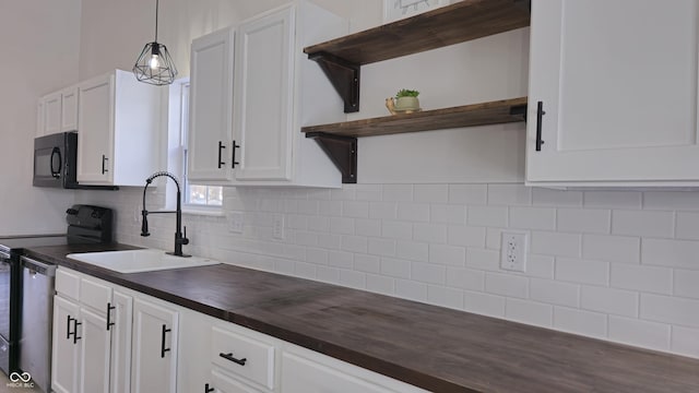 kitchen with pendant lighting, white cabinets, black appliances, decorative backsplash, and sink