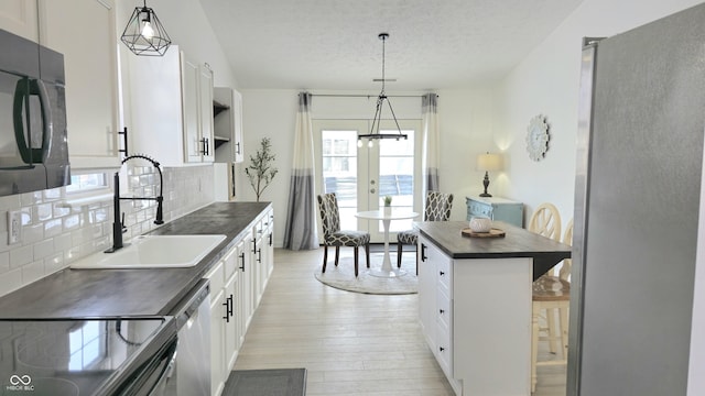 kitchen featuring decorative light fixtures, white cabinetry, a textured ceiling, and tasteful backsplash