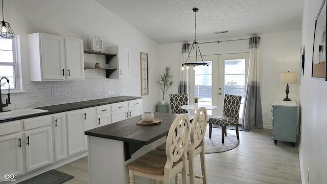 kitchen featuring tasteful backsplash, white cabinetry, hanging light fixtures, sink, and a kitchen island