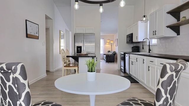 kitchen featuring sink, white cabinetry, electric stove, and stainless steel fridge