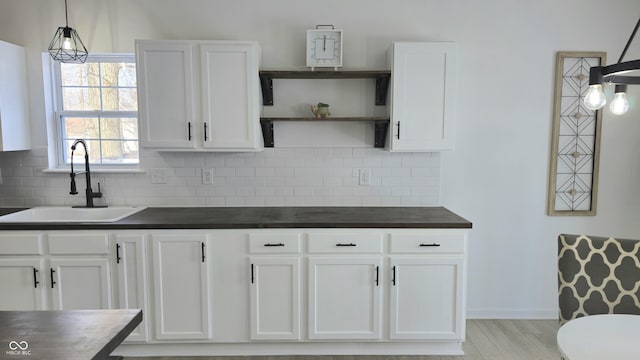 kitchen with sink, white cabinets, and decorative light fixtures