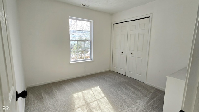 unfurnished bedroom with light colored carpet and a closet