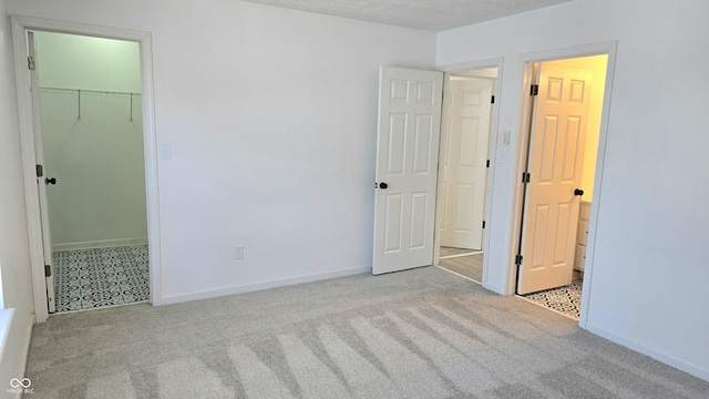 unfurnished bedroom featuring light colored carpet, a closet, and a walk in closet