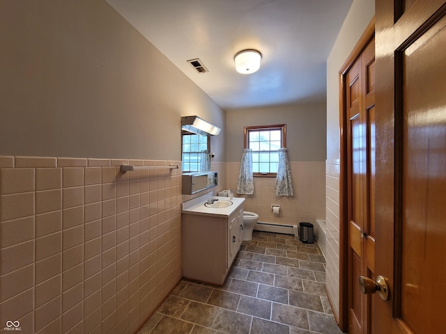 bathroom featuring toilet, vanity, tile walls, and a baseboard heating unit