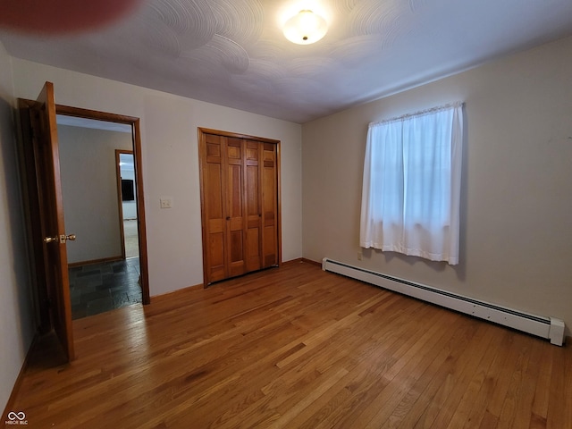 unfurnished bedroom featuring hardwood / wood-style floors, a closet, and a baseboard radiator