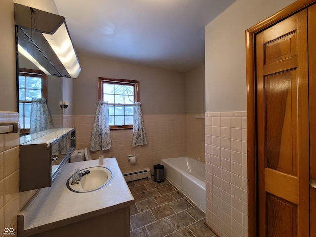 bathroom with toilet, vanity, tile walls, a baseboard heating unit, and a bathtub