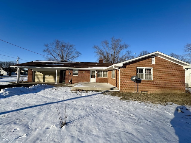 snow covered rear of property with a carport