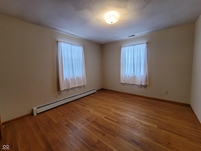 spare room featuring a baseboard heating unit and light hardwood / wood-style flooring