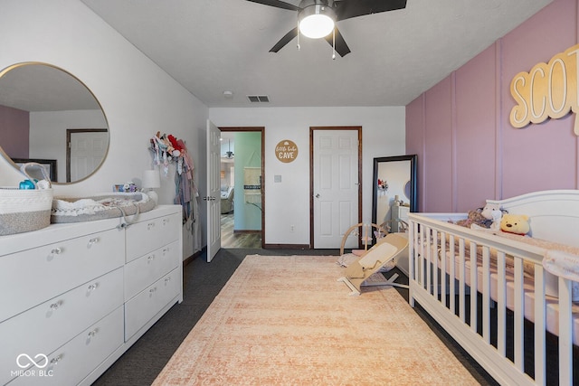 carpeted bedroom featuring ceiling fan and a nursery area