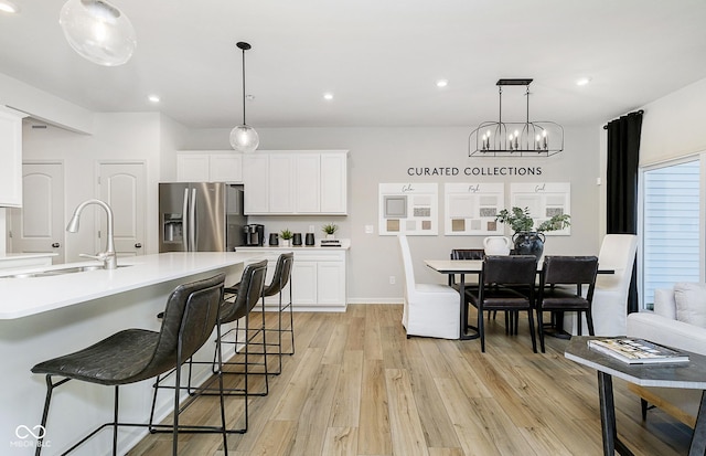 kitchen featuring pendant lighting, white cabinetry, stainless steel fridge, and light hardwood / wood-style flooring