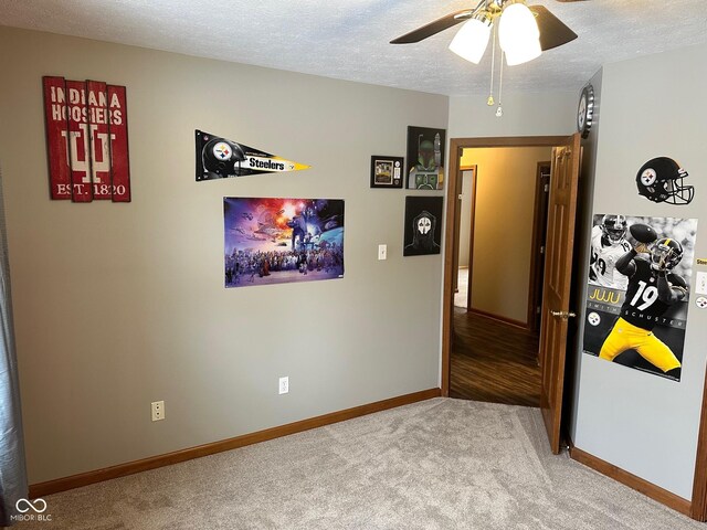 carpeted spare room featuring a textured ceiling and ceiling fan