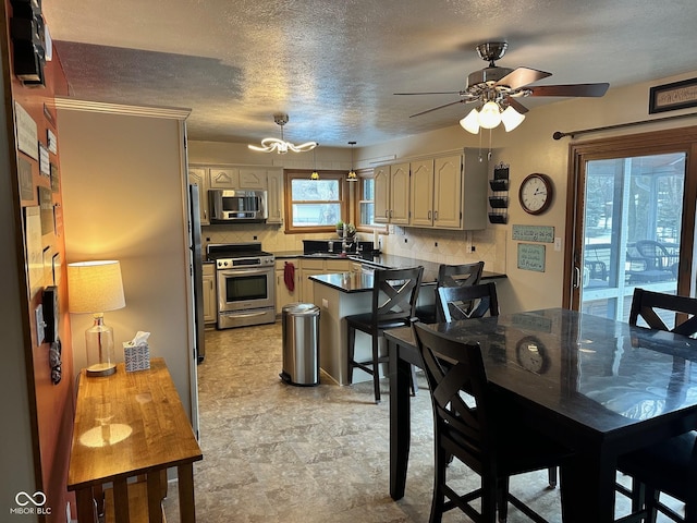 kitchen featuring a textured ceiling, stainless steel appliances, decorative backsplash, kitchen peninsula, and a breakfast bar