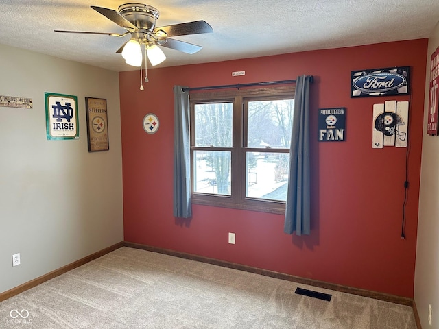 empty room with a textured ceiling, ceiling fan, and carpet