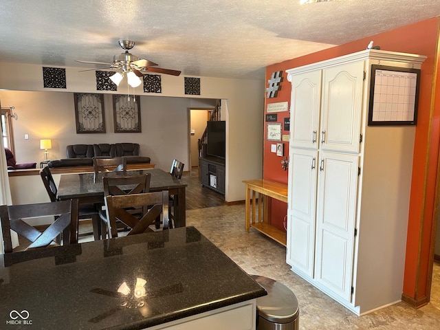 kitchen with a textured ceiling, ceiling fan, and white cabinetry