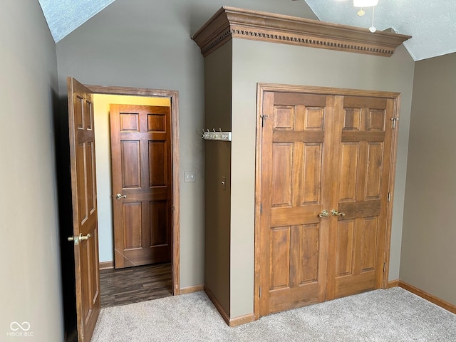 hallway with a textured ceiling, light carpet, and lofted ceiling