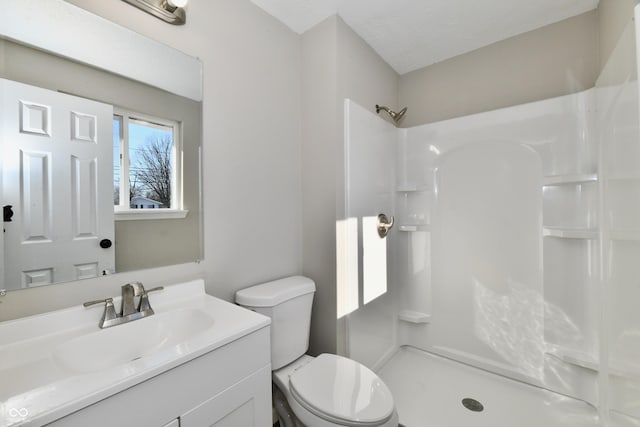 bathroom featuring toilet, a shower, and vanity