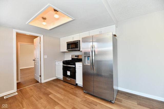 kitchen with white cabinets, stainless steel appliances, and light hardwood / wood-style flooring