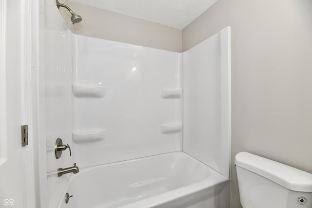 bathroom with toilet, bathing tub / shower combination, and a textured ceiling