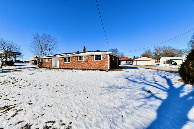 snow covered back of property featuring a garage