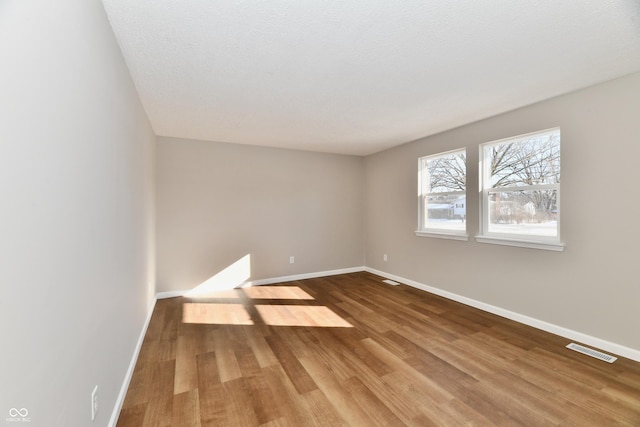 spare room featuring a textured ceiling and hardwood / wood-style floors