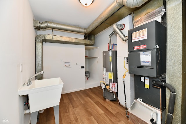 utility room with heating unit, sink, and gas water heater