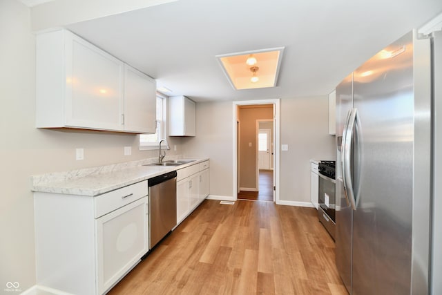 kitchen with light hardwood / wood-style flooring, sink, stainless steel appliances, and white cabinetry