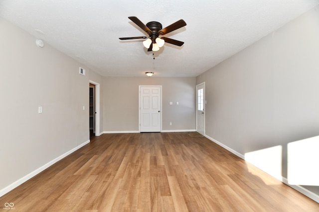 spare room with a textured ceiling, ceiling fan, and light hardwood / wood-style flooring