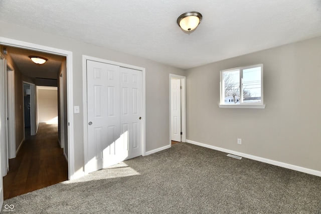 unfurnished bedroom featuring a closet, dark carpet, and a textured ceiling