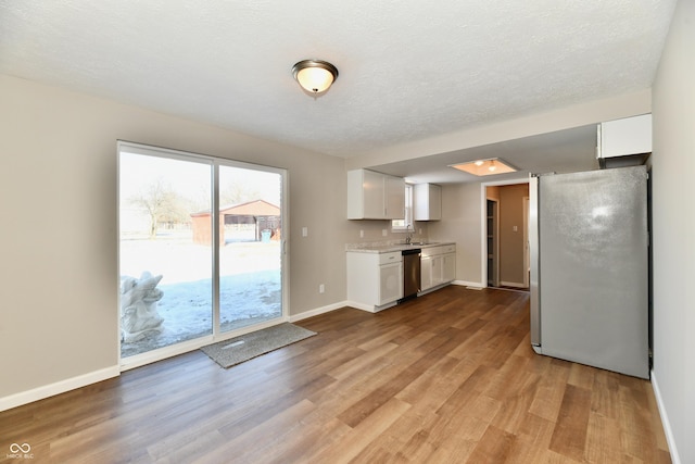 kitchen featuring appliances with stainless steel finishes, white cabinets, a textured ceiling, light hardwood / wood-style flooring, and sink