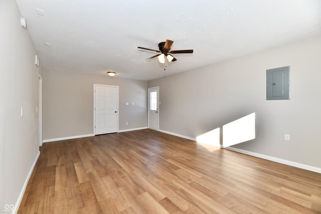 empty room with ceiling fan, wood-type flooring, electric panel, and a textured ceiling