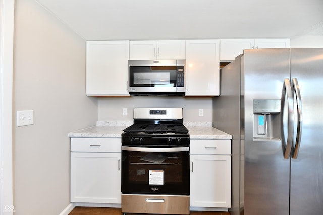 kitchen featuring light stone counters, stainless steel appliances, and white cabinetry