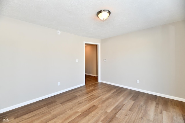 unfurnished room featuring light hardwood / wood-style floors and a textured ceiling