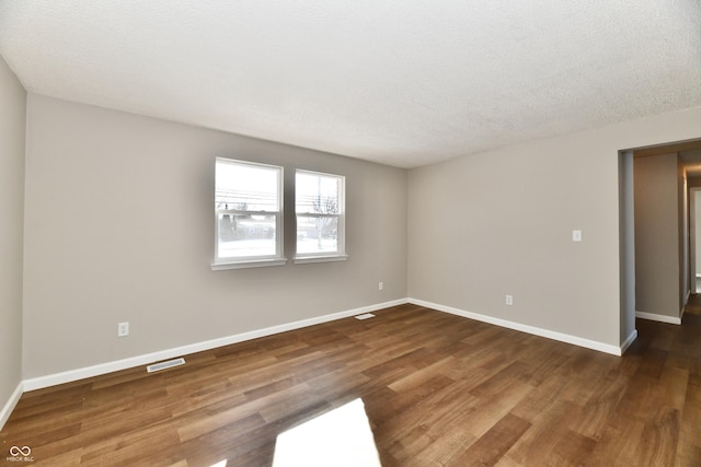 unfurnished room with dark hardwood / wood-style flooring and a textured ceiling