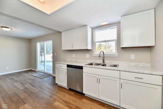 kitchen featuring white cabinets, sink, light wood-type flooring, light stone counters, and stainless steel dishwasher