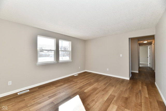 unfurnished room with hardwood / wood-style flooring and a textured ceiling