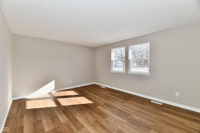 unfurnished room featuring wood-type flooring and a textured ceiling