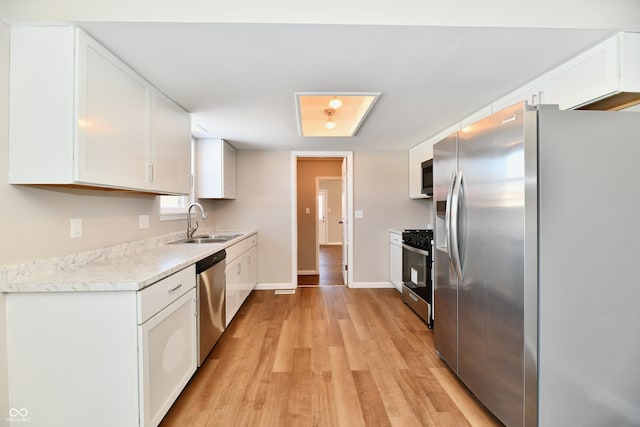 kitchen featuring stainless steel appliances, light hardwood / wood-style floors, white cabinetry, and sink