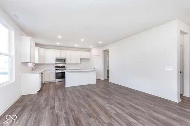 kitchen with a kitchen island, sink, appliances with stainless steel finishes, white cabinets, and dark hardwood / wood-style flooring